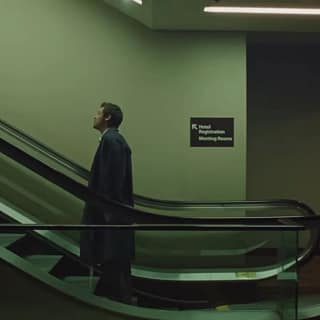 Frame do clipe “Aperture”, de Harry Styles: cantor em pé em uma escada rolante, em cenário urbano com luz fria e atmosfera cinematográfica.