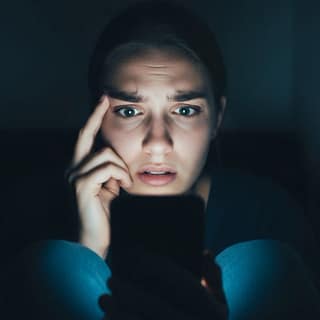 Mulher assustada olhando para o celular, representando a cultura do cancelamento e a autocensura nas redes sociais