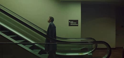 Frame do clipe “Aperture”, de Harry Styles: cantor em pé em uma escada rolante, em cenário urbano com luz fria e atmosfera cinematográfica.