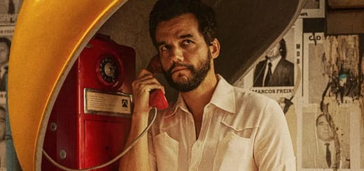 Wagner Moura em cena do filme O Agente Secreto usando um orelhão durante a ditadura militar no Brasil