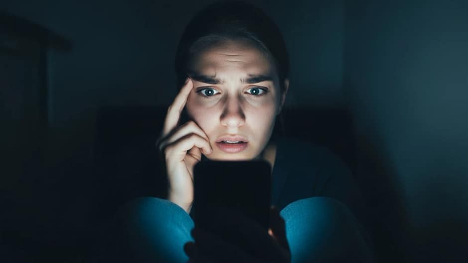 Mulher assustada olhando para o celular, representando a cultura do cancelamento e a autocensura nas redes sociais